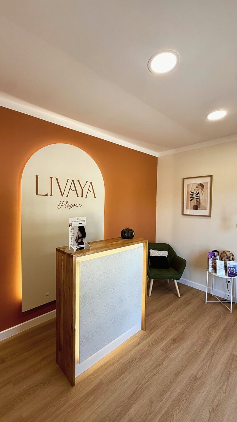 Accueil du centre Livaya : comptoir en bois lumineux devant une arche claire portant le nom Livaya Flayosc, mur terracotta et fauteuil vert