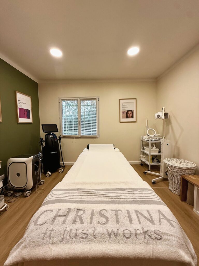 Cabine de soins lumineuse vue depuis la table de soin, avec fenêtre, appareils et panier en osier