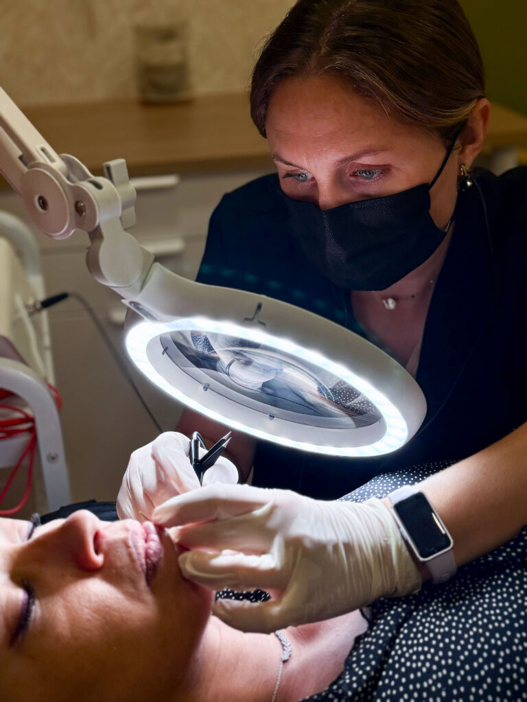 Séance de thermolyse : la praticienne travaille avec précision sous une loupe éclairante